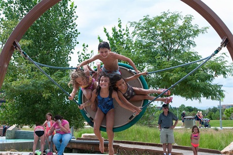 four kids on disk swing in Centennial Center Park