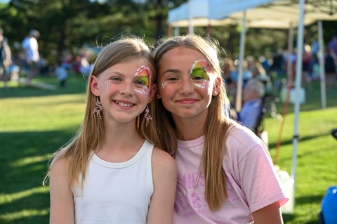 Two girls with their face painted at a summer social event