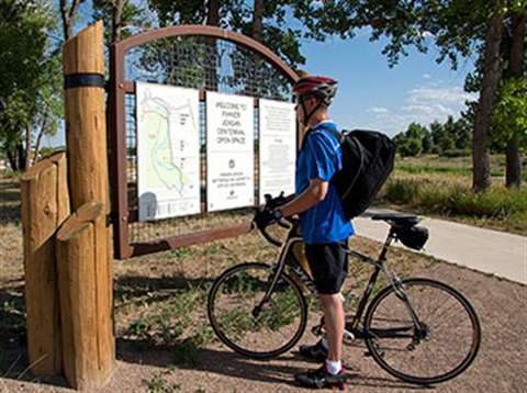 bicyclist looking at trail sign