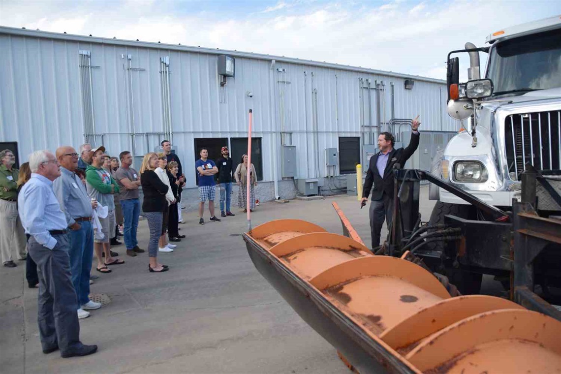 Image of Public Works employee showing snow plow to visitors.